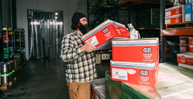 Warehouse worker stacking Yakima Chief Hops boxes on pallets