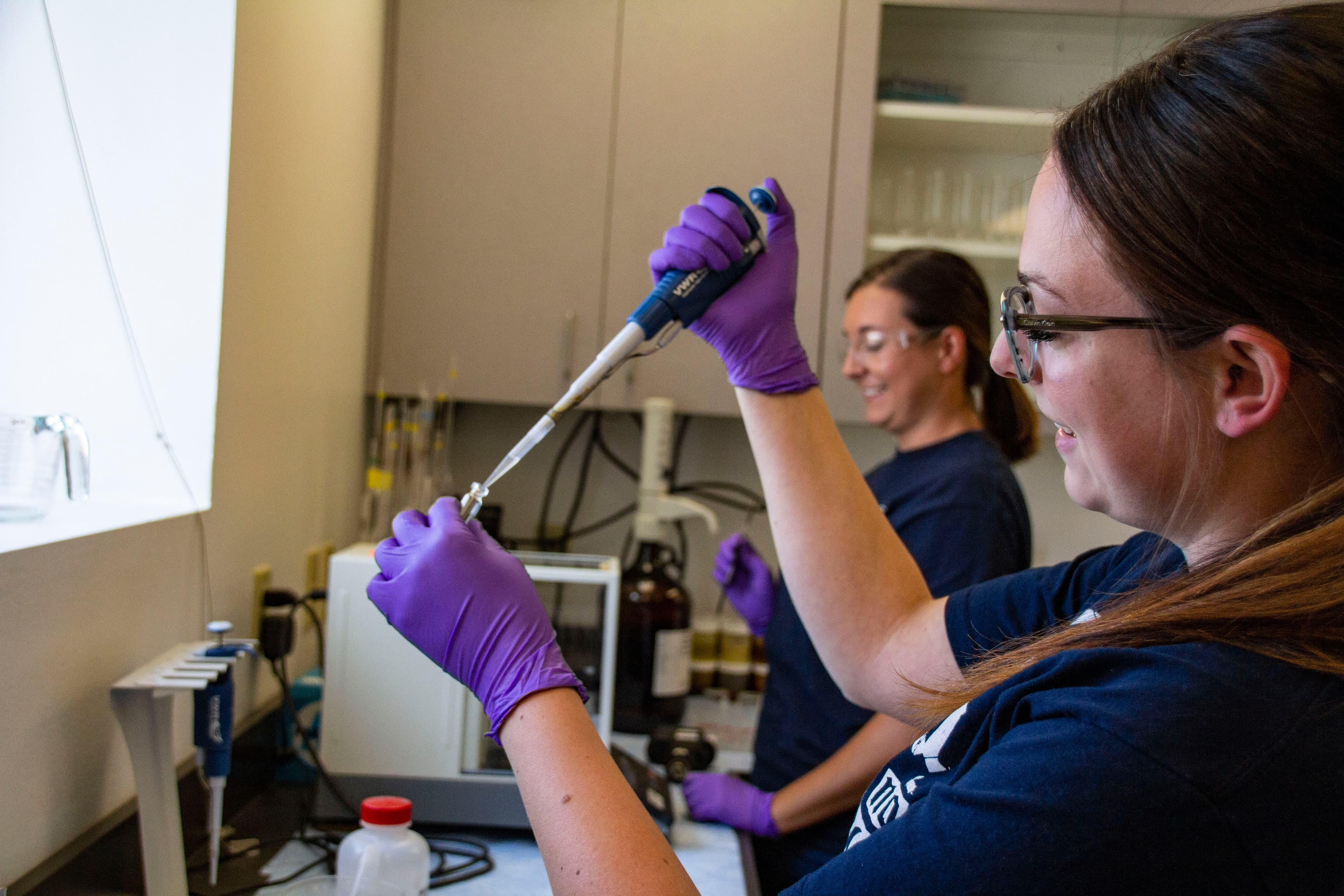 Image of two women in a lab holding a pipette