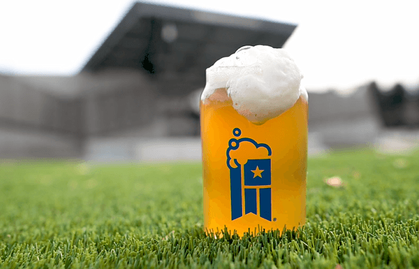 outdoor venue with glass of beer in the front with foam