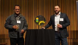 Two men with beer in their glasses standing with the clean energy award